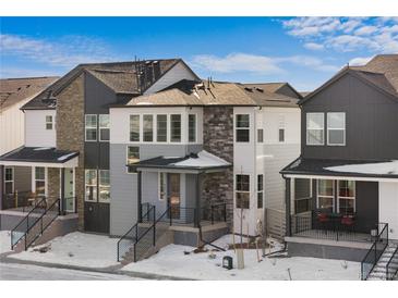 Modern two-story home with gray and white exterior, and snowy front yard at 7210 Watercress Dr, Littleton, CO 80125