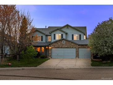 Charming two-story home with a stone accent, three-car garage, and well-maintained lawn at twilight at 1126 S Davenport Ct, Erie, CO 80516