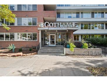 A brick Gotham building entrance with a vintage-looking sign, landscaping, steps and a sidewalk at 1196 N Grant St # 407, Denver, CO 80203
