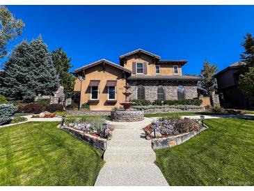 Stunning home with lush landscaping, a stone water fountain, and a welcoming walkway at 9552 E Silent Hills Pl, Lone Tree, CO 80124