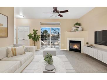 Bright living room with a fireplace, ceiling fan and sliding door to a balcony with seating at 8422 S Upham Way # G47, Littleton, CO 80128