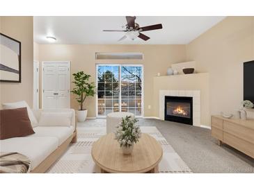 Bright living room with a fireplace, a ceiling fan, and a sliding glass door leading to an outdoor balcony at 8422 S Upham Way # G47, Littleton, CO 80128