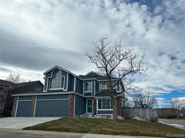 Two-story house with a gray exterior, brick accents, and a three-car garage at 245 Dunhill St, Castle Rock, CO 80104