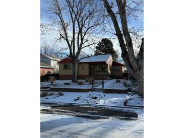 Charming single-story home featuring a brick facade, red roof, and snow-covered front yard with mature trees at 2060 S Washington St, Denver, CO 80210