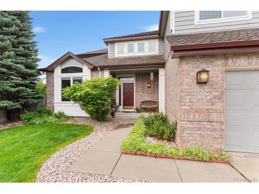 Charming brick home with a cozy front porch and landscaped garden for curb appeal at 6643 Orion Ct, Arvada, CO 80007