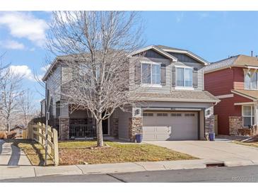 Two-story house with gray siding, a large driveway and landscaping at 4942 S Zephyr St, Littleton, CO 80123