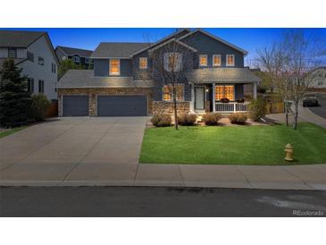 Charming two-story home with a three car garage and a welcoming front porch at twilight at 3475 Golden Spur Loop, Castle Rock, CO 80108