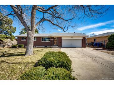 Brick home featuring a well-maintained lawn, mature trees, and attached two car garage at 1302 S Cape Way, Lakewood, CO 80232