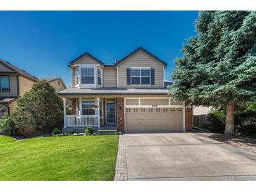 Charming two-story home featuring manicured lawn, a front porch, and attached two-car garage at 21238 Snowshoe Ln, Parker, CO 80138