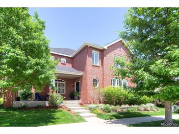 Inviting two-story brick home featuring a well-manicured lawn and mature trees at 7527 E Severn Pl, Denver, CO 80230