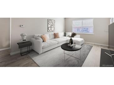 Bright living room featuring a white sectional sofa and coffee table at 384 S Decatur St, Denver, CO 80219