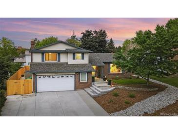 Charming two-story home with brick and siding, manicured lawn, and a two-car garage on a tree filled lot at 15034 E Floyd Ave, Aurora, CO 80014