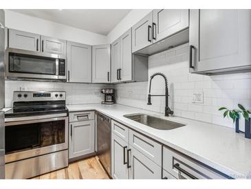 Modern kitchen featuring stainless steel appliances, white subway tile backsplash, gray cabinets, and quartz countertops at 888 N Logan St # 5A, Denver, CO 80203