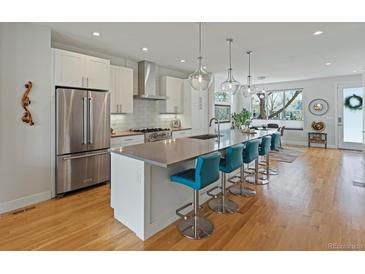 Modern kitchen features stainless appliances, an oversized island with seating, and stylish pendant lighting at 4525 N Raleigh St, Denver, CO 80212