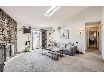 Bright living room features a stone fireplace, plush carpet, and sliding glass doors to a patio at 10150 E Virginia Ave # 7-302, Denver, CO 80247