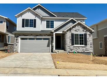 Charming two-story home with a stone facade, gray siding, black shutters, and an attached two-car garage at 25323 E Warren Pl, Aurora, CO 80018