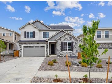 Beautiful two-story home featuring stone accents, gray siding, a two-car garage, and manicured landscaping at 25323 E Warren Pl, Aurora, CO 80018