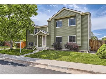 Inviting two-story home with green siding, a well-manicured lawn, and mature trees for shade at 5713 Whitechapel St, Castle Rock, CO 80104
