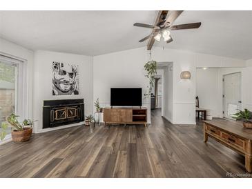 Inviting living room featuring a fireplace, modern ceiling fan, and wood-look laminate flooring at 5532 Umatilla St, Denver, CO 80221