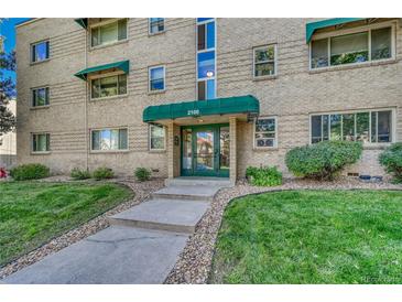 Inviting brick building entrance with green awning, glass door, and well-manicured lawn at 2100 N Franklin St # 15, Denver, CO 80205