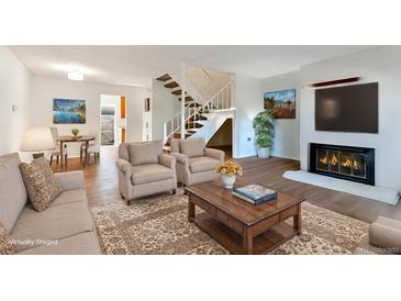 Bright living room featuring a fireplace, staircase, and comfortable seating at 1235 S Monaco Pkwy, Denver, CO 80224