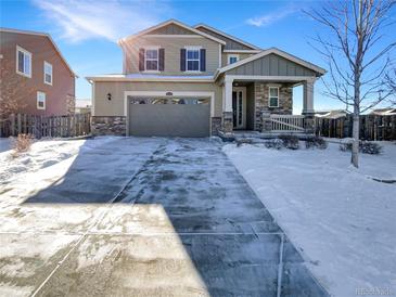 Two-story house with a gray and beige exterior, stone accents, and a snow-covered driveway at 26226 E Canal Pl, Aurora, CO 80018