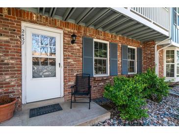 Inviting front door with charming brickwork, gray shutters, and beautiful landscaping adds curb appeal at 2437 E Geddes Pl, Centennial, CO 80122