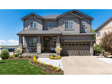 Charming gray two-story home with stone accents, a welcoming front porch and manicured lawn at 110 Ferris Ln, Erie, CO 80516