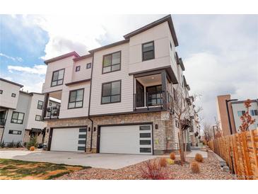 Modern three-story townhome with white siding, stone accents, and two-car garage at 1990 S Holly St # 4, Denver, CO 80222