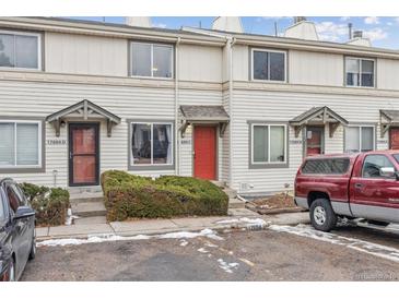 Townhouse exterior features neutral siding, colorful front doors, and manicured bushes, with a glimpse of winter landscape at 17694 E Loyola Dr # C, Aurora, CO 80013