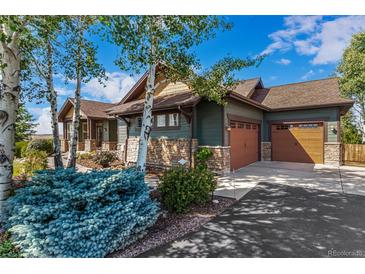 Craftsman-style home featuring a stone facade, a three-car garage, and tasteful landscaping at 1505 Legacy Trl, Elizabeth, CO 80107
