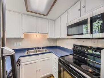 Compact kitchen featuring white cabinets, blue countertops, and modern appliances at 1720 S Ammons St # A, Lakewood, CO 80232