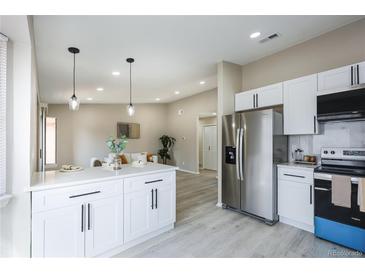 Bright, renovated kitchen with stainless steel appliances and light gray flooring open to the living area at 1075 S Garrison St # 201, Lakewood, CO 80226