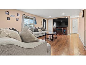 Inviting living room with a decorative fireplace, plush seating and wood-style floors at 7511 Locust St, Commerce City, CO 80022