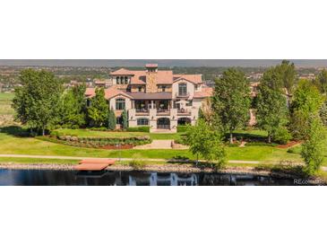 Luxury home featuring lush landscaping, a dock, and expansive lawn overlooking a serene lake at 1820 Mallard Dr, Broomfield, CO 80020