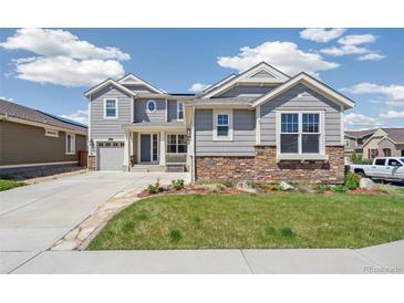 Beautiful two-story home with gray siding, stone accents, well-manicured lawn, and a two-car garage at 19471 W 59Th Ave, Golden, CO 80403