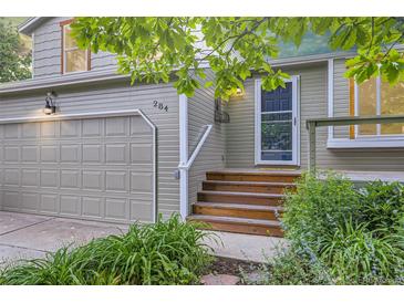 Inviting home entrance features wooden steps, a storm door, and a well-maintained front yard with lush greenery at 284 S Lincoln Ave, Louisville, CO 80027