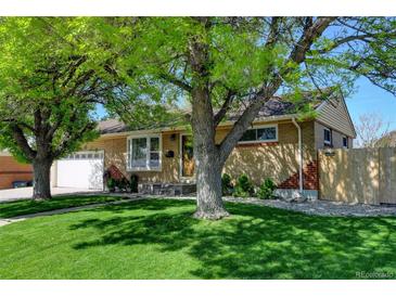 Charming brick home featuring a well-manicured lawn and mature trees providing ample shade at 10769 Carrol Ln, Northglenn, CO 80233