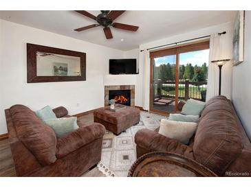 Inviting living room featuring a cozy fireplace, plush seating, and a sliding glass door to a deck at 34 Highfield Trl # 311, Breckenridge, CO 80424