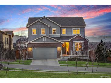 Charming two-story home features a brick and gray exterior with a two-car garage, lush lawn, and mountain views at 12917 Fox St, Westminster, CO 80234