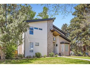 Modern exterior elevation featuring a mix of stucco and stone, set against a backdrop of mature trees and manicured lawn at 1533 S Columbine St, Denver, CO 80210