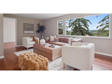 Bright living room featuring a stylish sofa, cozy armchairs, natural light, and a view at 30321 Chestnut Dr, Evergreen, CO 80439