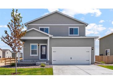 Two-story home featuring a large two car garage, gray siding, and manicured front lawn at 7220 Big Thompson Ct, Frederick, CO 80530