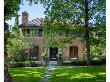 Brick home with a tile roof, mature trees, and a landscaped lawn at 559 N Williams St, Denver, CO 80218