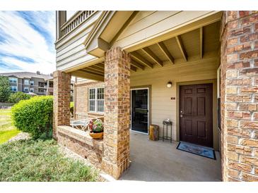 Cozy covered patio with brick columns, seating area, and a view of the surrounding greenery at 12820 Ironstone Way # 103, Parker, CO 80134