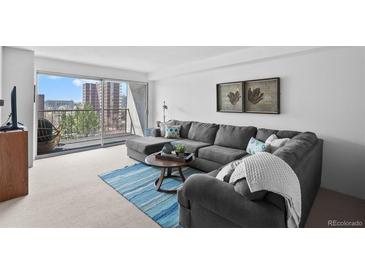 Bright living room with gray sectional, balcony access, and city views at 2 Adams St # 806, Denver, CO 80206