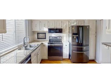 Well-lit kitchen features stainless steel appliances, granite countertops, and white cabinets at 1050 S Monaco Pkwy # 38, Denver, CO 80224