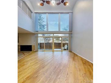 Bright living room with a fireplace, beautiful hardwood floors, and large windows with access to the outdoors at 1050 S Monaco Pkwy # 38, Denver, CO 80224