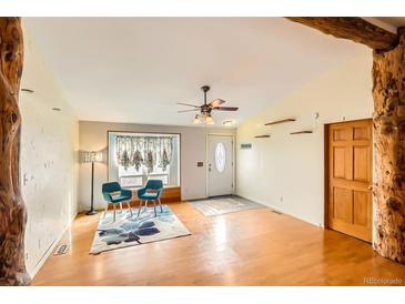 Inviting living room featuring hardwood floors, a ceiling fan, and a sunlit window with decorative curtains at 441 Johnson St, Frederick, CO 80530
