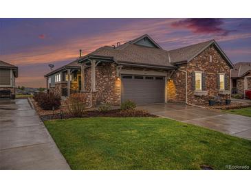 Charming single-Gathering home showcasing a stone exterior, attached garage, and well-maintained lawn at dusk at 24943 E Phillips Pl, Aurora, CO 80016
